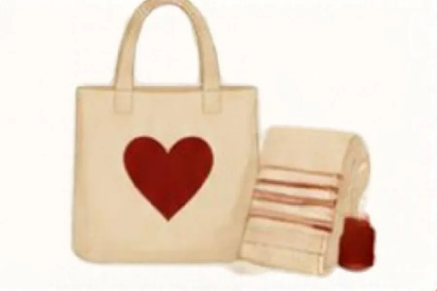 A handmade tote bag with a red heart beside folded fabric.